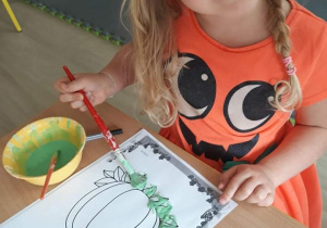 Dziewczynka maluje dynię rosnącą farbą