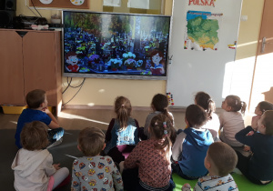 Dzieci patrzą w ekran na którym widać cmentarz