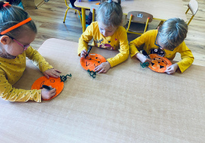 Przedszkolaki tworzą zabawne dynie na talerzyku papierowym.