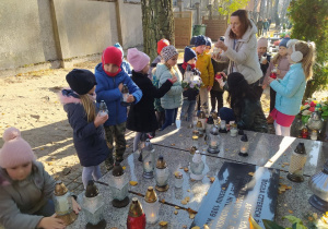 dzieci układają znicze na pomniku
