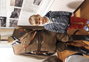 Chłopiec stoi przy manekinie na którym znajduje się dawny strój żołnierski