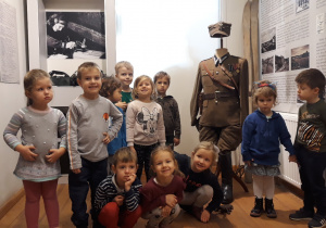 Dzieci stoją przy manekinie na którym znajduje się mundur żołnierza