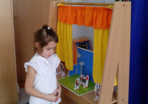 Dziewczynka ustawiła element inscenizacji na planszy w teatrzyku teatralnym.