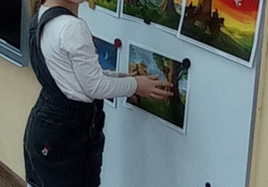 Dziewczynka zawiesza na tablicy obrazek