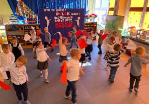 Dzieci tańczą z biało - czerwonymi kartkami.