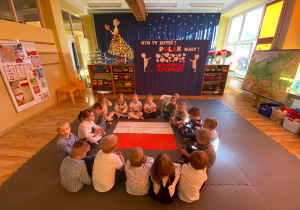 Dzieci pozują z ułożona na macie flagą Polski.