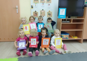 Dzieci pokazują swoją pracę plastyczną , kolorowankę z wybranym przez siebie prawem dziecka