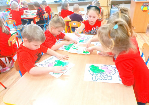 Przedszkolaki malują zieloną farbą liście buraczka.