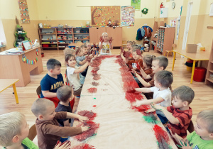 Dzieci pokazują do zdjęcia swoje dłonie pokryte brązową farbą.