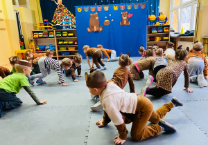 Dzieci poruszają się według instrukcji nauczycielki podczas zabawy ruchowej na macie.