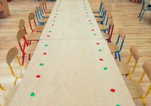 Złączone stoliki z nałożonymi farbami czerwoną i zieloną dla każdego dziecka.