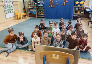 Przedszkolaki w misiowych opaskach z uszami oglądają film edukacyjny o misiach.