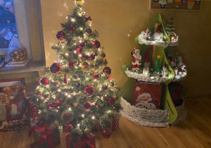 Udekorowane świąteczne drzewko i świąteczny kącik w blasku światełek choinkowych.