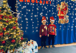 Filipek i Albercik pozują na tle Mikołajkowej dekoracji.