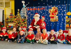 Grupa dzieci pozuje do zdjęcia z Mikołajem.