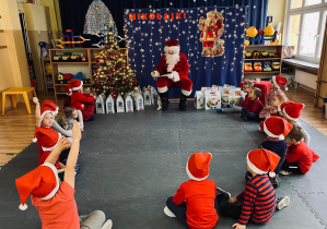 Dzieci rozmawiają z Mikołajem, który odwiedził przedszkole.