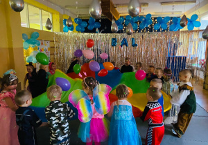 Przedszkolaki podrzucają kolorowe balony na chuście.