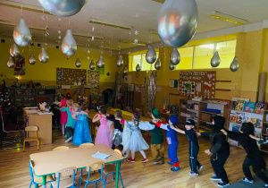 Przedszkolaki utworzyły pociąg i tańczą w rytm muzyki.