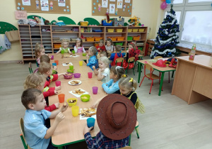 Dzieci siedzą przy stolikach na poczęstunku w przerwie balu