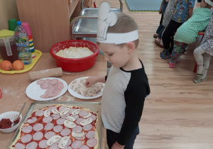 Wiktorek układa pieczarki na pizzy.