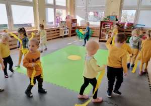 Dzieci idą w kole z żółtymi paskami bibuły