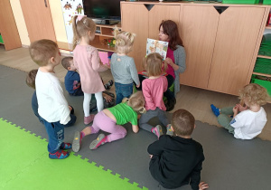 Dzieci słuchają ilustowanych opowieści o dinozaurach