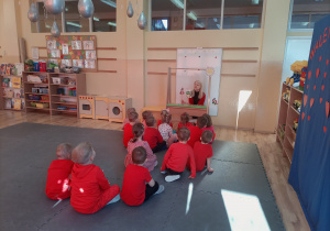 Dzieci siedzą przed teatrzykiem, nauczycielka pokazuje sylwety biedronki i żuka.