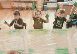 Dzieci pokazują zielone dłonie po mieszaniu farby.