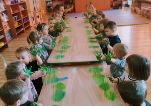 Dzieci pokazują swoje rączki po otrzymaniu zielonego koloru z farb.