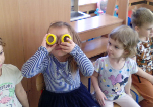 Dziewczynka spogląda przez specjalne okulary i sprawdza jak widzą mrówki