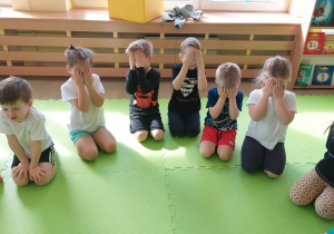 Dzieci siedzą z zamkniętymi oczami