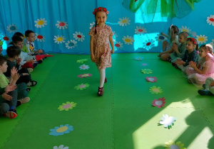 Laura wesołym krokiem prezentuje swój strój na zielonym dywanie