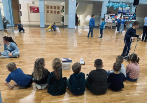 Przedszkolaki przyglądają się uczniom sterującym roboty.