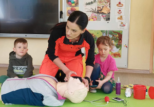 Pani ratownik pokazuje dzieciom, jak sprawdzić czy osoba nieprzytomna oddycha
