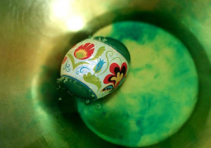 Zabarwione na zielono jajo w misce z gorącą wodą- na jajku owijka z ludowym wzorem
