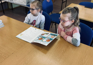 Wiktoria i Milenka oglądają czasopismo dla dzieci "Świerszczyk".