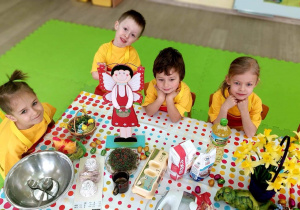 Dzieci siedzą przy stole, na którym są składniki potrzebne do upieczenia babeczek