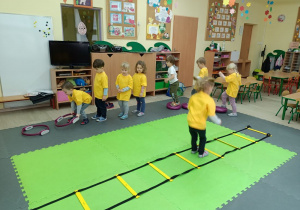 Dzieci skacza przez drabinke gimnastyczną