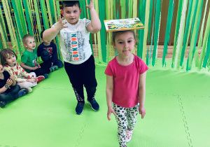 Julka i Mikołaj spacerują z książkami na głowie.
