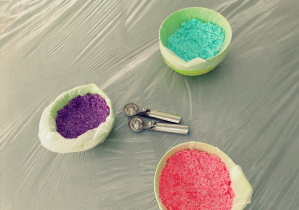 Trzy miski z kolorową ryżoliną i łyżki do nakładania lodów.