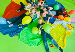 Chłopcy pozują do zdjęcia leżąc na kolorowej chuście.