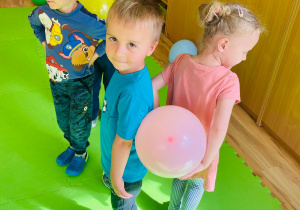 Dzieci starają się nie upuścić balonów, które trzymają pomiędzy plecami.