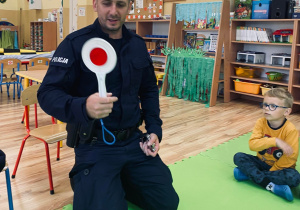 Pan policjant pokazuje dzieciom lizak policyjny.