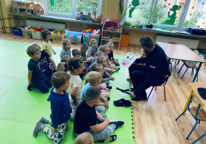 Tata Hani czyta dzieciom książeczkę pt. "Kicia Kocia zostaje policjantką"
