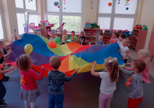 Dzieci śmieją się podczas podrzucania balonów za pomocą chusty animacyjnej.