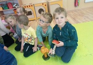 Dzieci oglądają przykładowe grzyby polskich lasów.