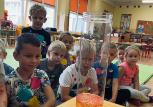 Przedszkolaki obserwują utworzone podczas eksperymentu wielkie kropki w naczyniu.