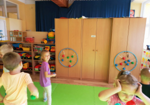 Przedszkolaki rzucają piłeczkami do celu powstałego z obręczy hula hop.