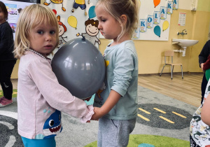 Dziewczynki tańczą trzymając balon.