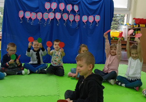 Jaś siedzący w kole podczas zabawy z lizakami.